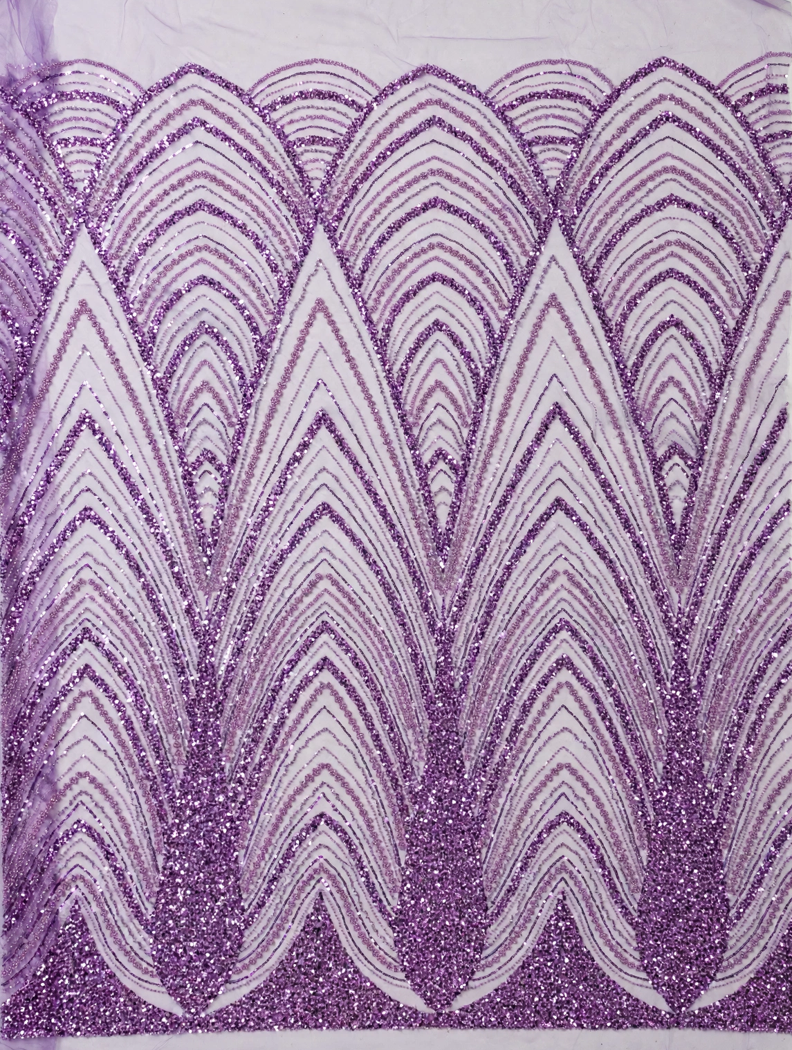Vue à plat du tulle perlé lilas à grands motifs de feuillage en arcs superposés et lignes brillantes.