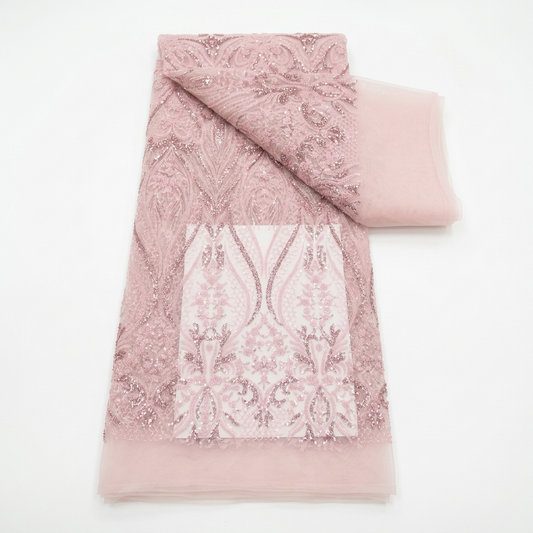 Tulle perlé rose poudré plié en longueur à motifs floraux et arabesques, avec un pan de tulle uni visible à droite.